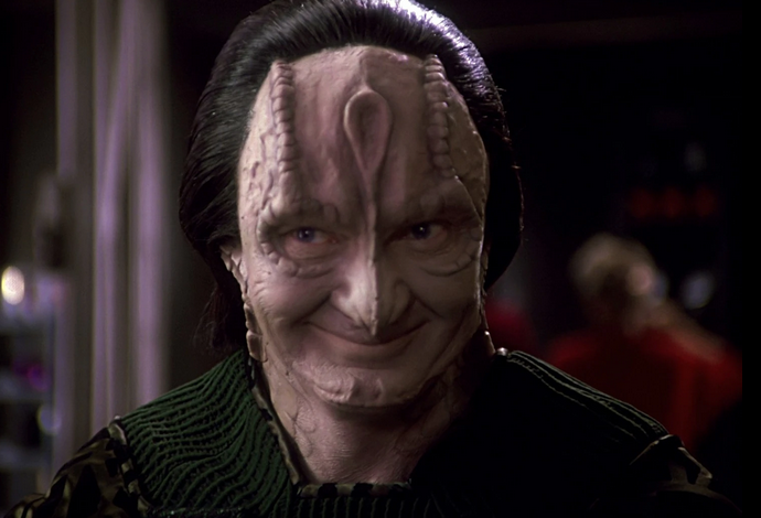 garak, a cardassian (lizard-like alien species) from ds9 smiling mischievously