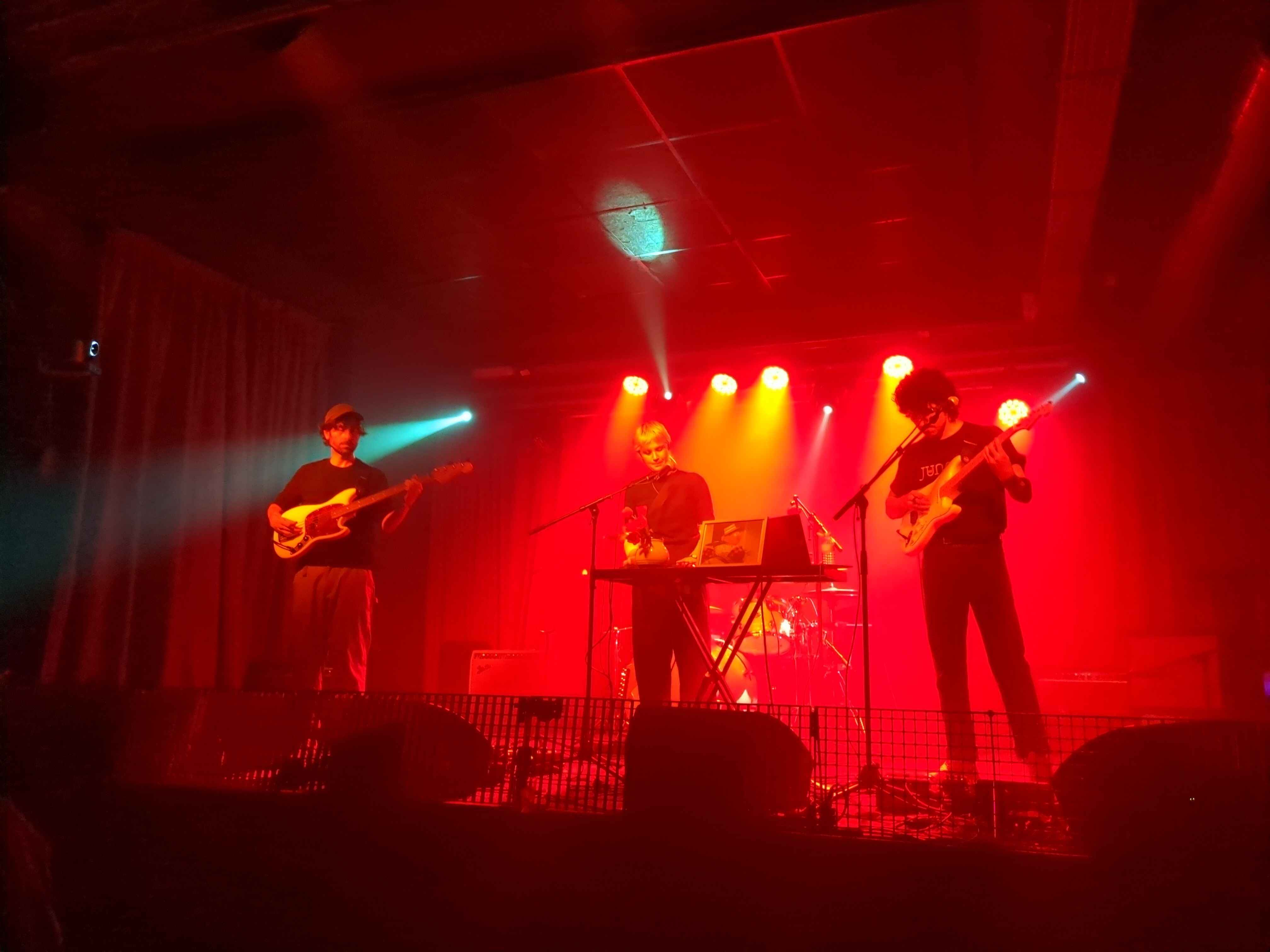 a glowing red concert hall with a band playing